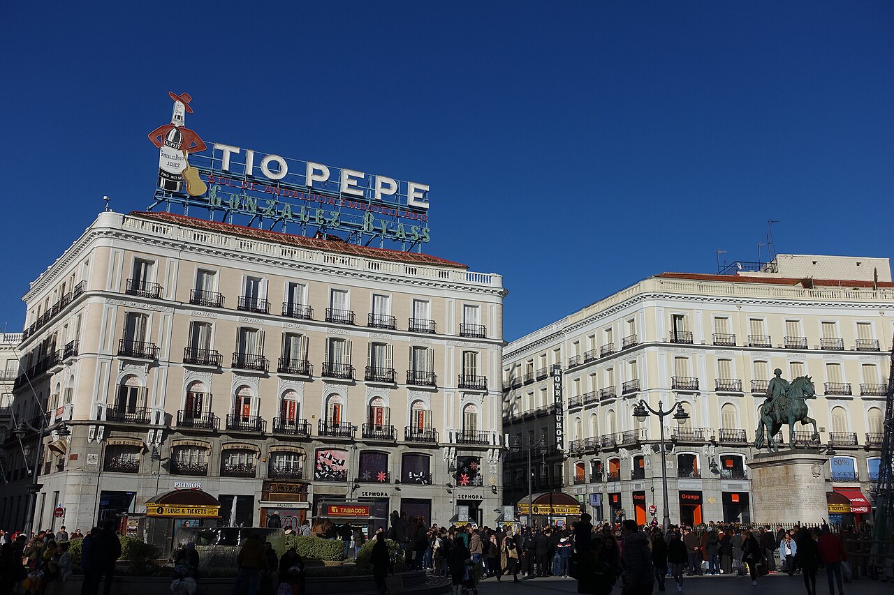 Peatones en la Puerta del Sol de Madrid ante los edificios de la plaza